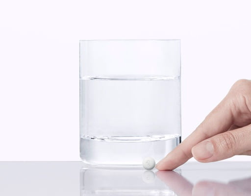 hand pushing pill and a glass of water